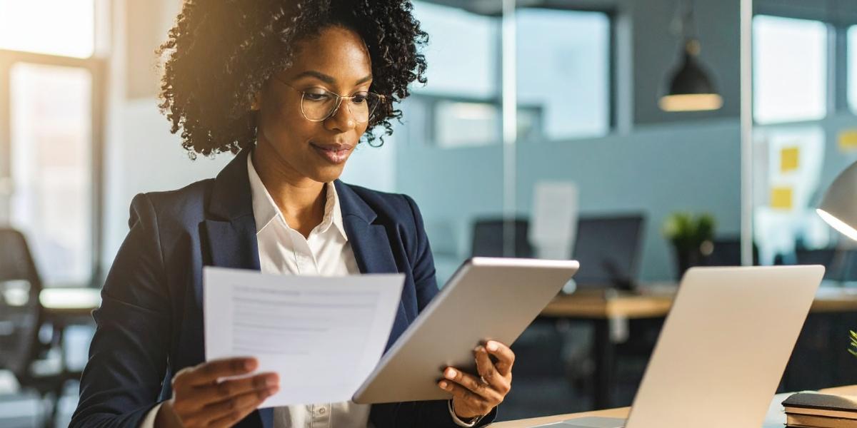 Business leader reviewing an IT audit report and compliance documentation on a tablet and laptop